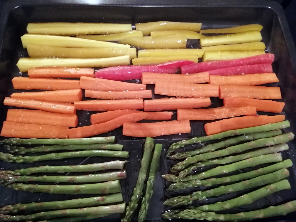 Rows of fresh carrots and asparagus displayed on a tray.