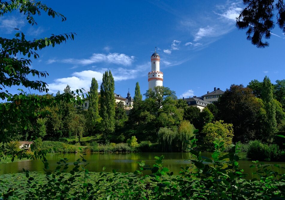 DSCF3164_Sept resized Bad Homburg Schloss in September — framed by lush greenery and calm waters under a clear blue sky.
